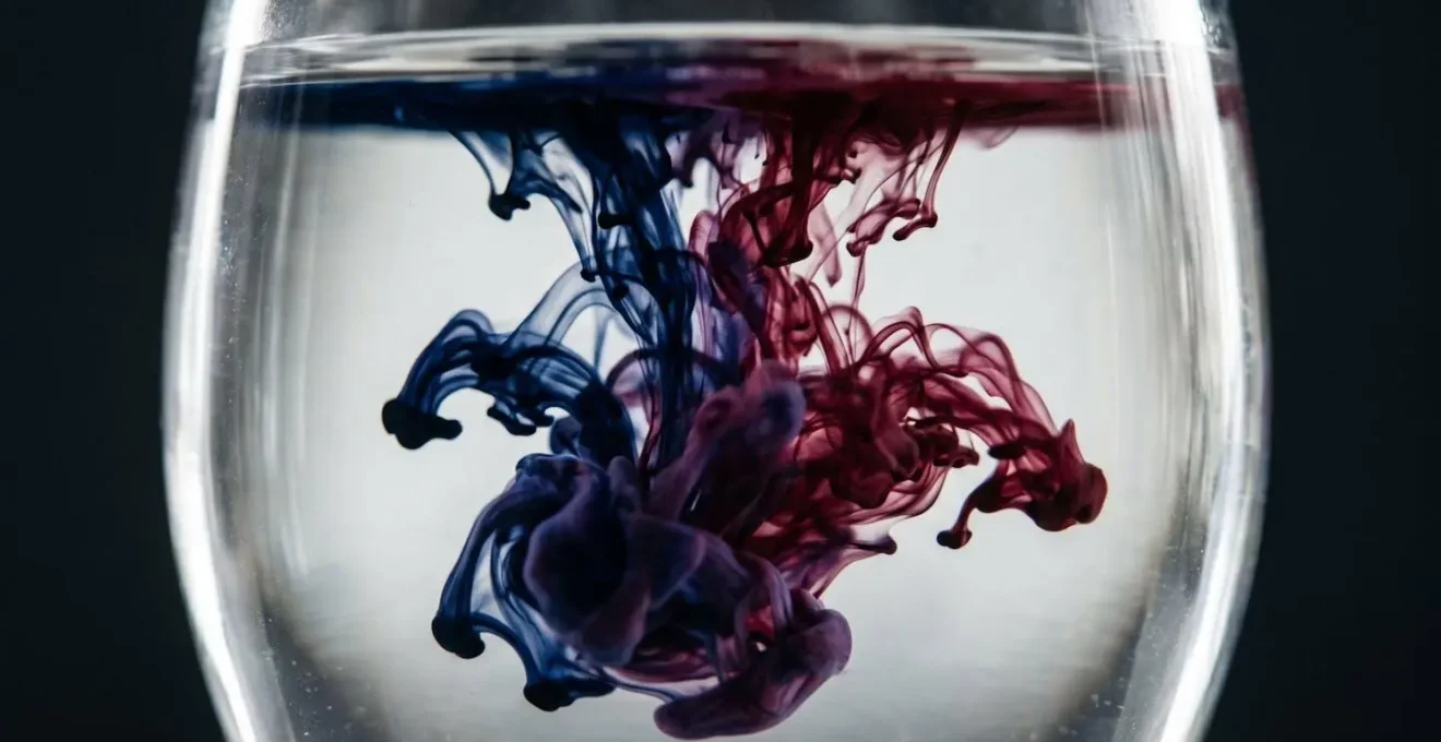 Macro photographie de deux encres colorées se mélangeant de manière incontrôlée dans l'eau claire d'un récipient transparent